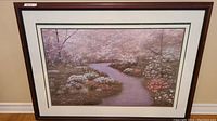 Framed painting showing the full landscape with a winding river and colorful flowering bushes and trees.