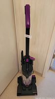 Front view of the upright vacuum cleaner showing the handle, dirt canister, and base.