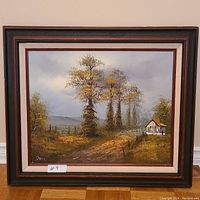 Full frontal view of the framed autumn road painting showing tall trees, a rural road, a small white house with a red roof, and a fence along the path.