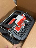 Photo of the box containing twelve brand new Bessey C-clamps with original tags, black frame and metal screws visible.
