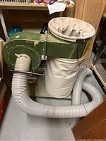 Front view of dust collector showing blower housing, cloth filter and collection bags, attached flexible hose