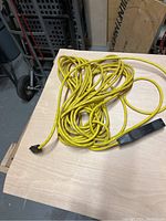 Full view of the yellow extension cord laid on a table, showing length and plug end.