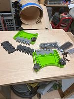 Feather Pro Featherboard kit parts laid out on wood surface. Kit includes two green curved featherboards, black feather inserts, clamps, and screws.