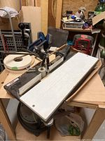 Wide angle view showing the Freud edge bander on a table with banding roll and miscellaneous edge banding taped rolls, alongside work area.