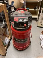 Front view of red Husky upright air compressor on wheels, hose wrapped around base.