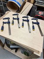 Five Irwin bar clamps laid out on a wooden board, showing overall size and condition with visible use marks.