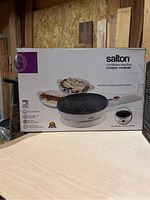 Box of Salton cordless electric crepe maker, white cordless device with non-stick surface shown on box