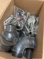 Photo shows a box filled with various black plastic elbow fittings and metal hose clamps for dust collection systems.