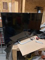 Front view of the Haier 40-inch LCD TV on a workbench with various tools around, showing the screen and physical condition.