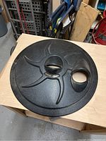 Top view of large black molded plastic cyclone lid showing one large hole and three smaller inlet holes.