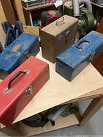 Four metal tool boxes on a table showing condition and color variation