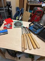 Overview of miscellaneous wood turning tools on table including chisels, cutting heads, sanding bosses, and boxes with bits