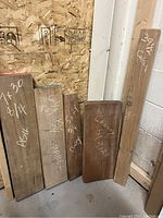 Photo showing five wood chunks of different species and sizes with chalk-written markings indicating approximate thickness and some length.