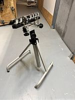 Single deluxe tripod-style outfeed roller support with multiple small plastic rollers and adjustable knobs on a silver metal frame.