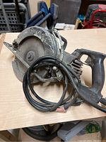Side view of the heavy duty worm drive circular saw showing metal casing, blade, and power cord coiled on handle.