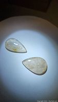 Two pear-shaped golden rutilated quartz cabochons showing transparency and golden rutile inclusions from top view.