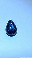 Pear-shaped sapphire cabochon showing six-rayed star asterism under directional lighting