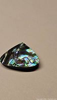 Pear-shaped natural abalone doublet gemstone with vivid iridescent colors and patterns visible in natural light.