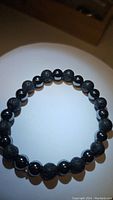 Photo of a chunky 8mm black lavastone and hematite bead stretch bracelet, alternating bead pattern, on a smooth surface.
