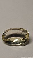 Close-up photo of an oval cut lemon citrine gemstone showing the faceted surface, color, and clarity.