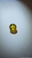 Close-up photo of the round cut yellow sapphire gemstone showing its color and inclusions