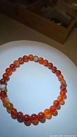 Close-up photo of the natural red agate beaded bracelet laid flat showing the round polished stones and vibrant color patterns.