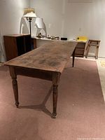 Full view of rectangular pine table showing plank top and turned legs.