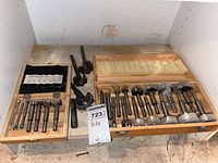 Two open wooden cases side by side showing 7 smaller bits on left and 12 larger bits on right