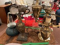 Vintage metal table lamps with various lamp shades displayed on a wooden table with Canadian flag and other background items visible.