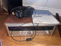 Overview of Pioneer TX-9100 tuner with woodgrain sides, silver front panel, Koss headphones on top, and operating manual beside unit