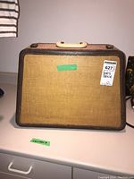 Front view of closed Singer 306K portable sewing machine hard case covered in beige fabric with brown textured border and plastic handle on top