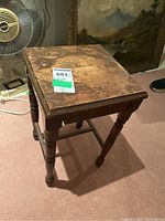 Top view of vintage wooden stool showing worn flat square seat and wood grain.
