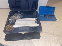 Photo showing blue screwdriver bit case, large black case with heavy-duty tool component, and size-labeled metal bars.