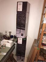 Photo of two boxed Canvas twig trees showing packaging with product branding and indicating size approximately 8 feet tall.