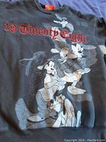 Front photo of black large sweatshirt with Disney characters Pluto, Goofy, Mickey Mouse, and Donald Duck printed on front and red '19 Twenty Eight' text.