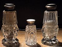 Three salt and pepper shakers—two larger matching pairs and one smaller distinct shaker, showing front view