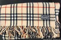 Close-up of scarf showing plaid pattern, fringe tassels, and 3elephant brand label.
