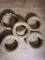 Five wicker wreaths laid out on wooden floor, showing all wreaths together.