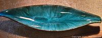 Top view of blue-green glazed leaf-shaped ceramic trinket tray showing color and shape details.