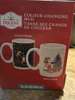 Box showing the mug's color changing feature: cold state with a black background and hot state with a white background illustrating dog, cat, and Christmas tree graphics.