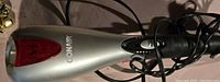 Close-up view of the silver and black Conair wand massager showing the red heat vent area and part of the power cord.