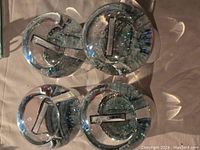 Four clear glass snow globes with shiny silver bases, arranged in square formation, showing the bases and top of globes with internal photo slots.