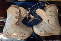 Side view of the pair of white K2 Plush snowboard boots showing outer panel and sole condition