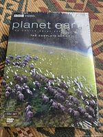 Front cover of the Planet Earth complete series DVD set showing a herd of animals in a natural landscape, sealed in shrink wrap.