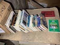 Box of various books straight view on a bench and surrounding area