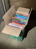 Box containing variety of youth books arranged upright showing colorful spines.