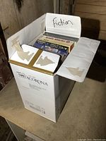 Box of novels labeled 'Fiction' with torn cardboard edges visible