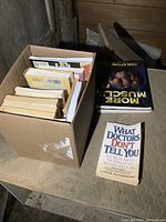 Box of books with some titles visible on top and on the outside