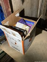 Photo of the box filled with novels showing multiple book spines in different colors.