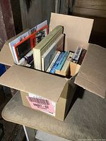 Photo showing the open box filled with various books stacked vertically and horizontally.
